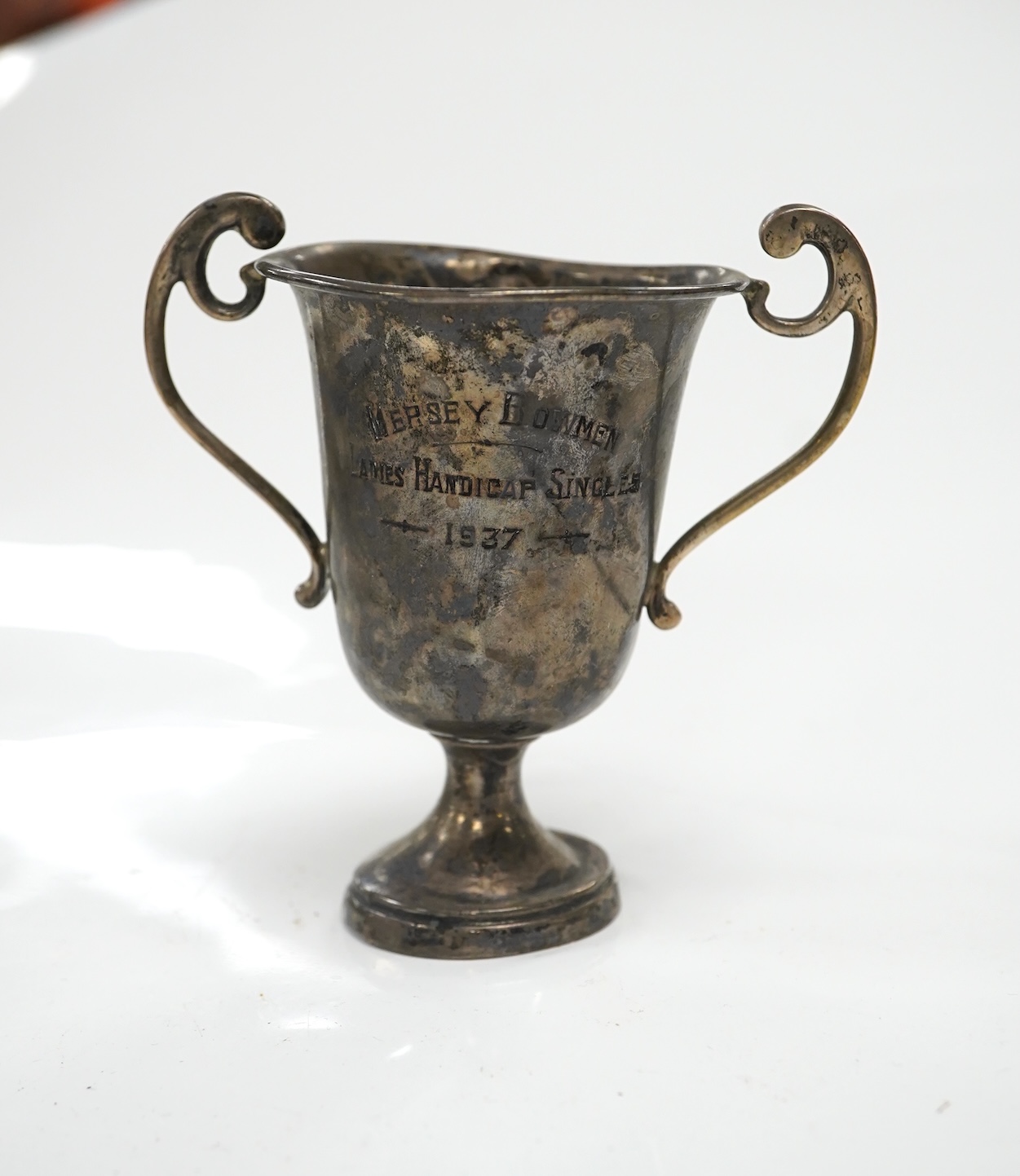 A William IV silver christening mug, London 1834, 10cm, a George III silver cream jug, London, 1799 and three small silver trophy cups. Condition - poor to fair